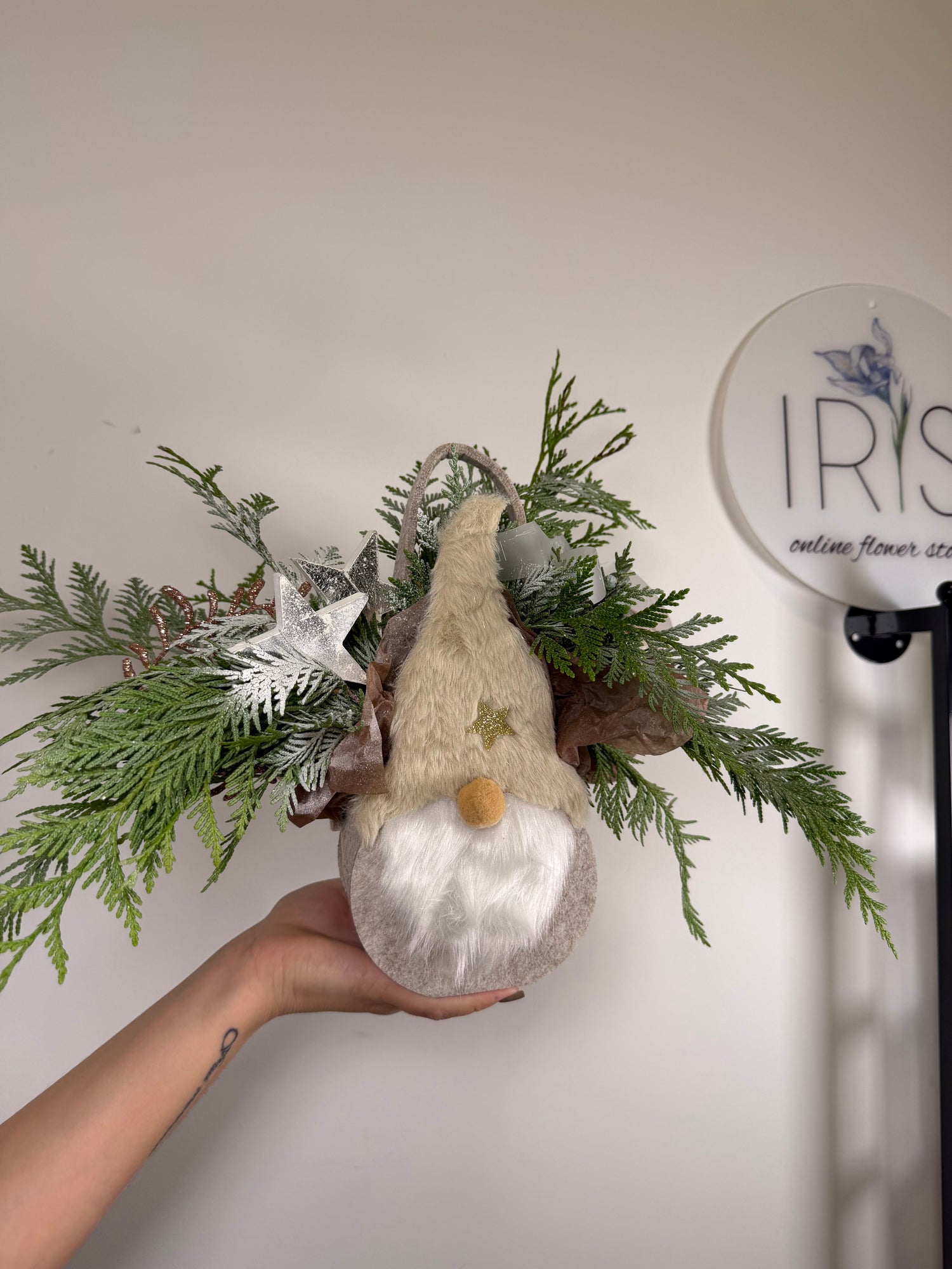 Holliday floral arrangement in a gnome-style fabric basket with fir branches, wooden toys,and ribbons - Iris Flowers Toronto